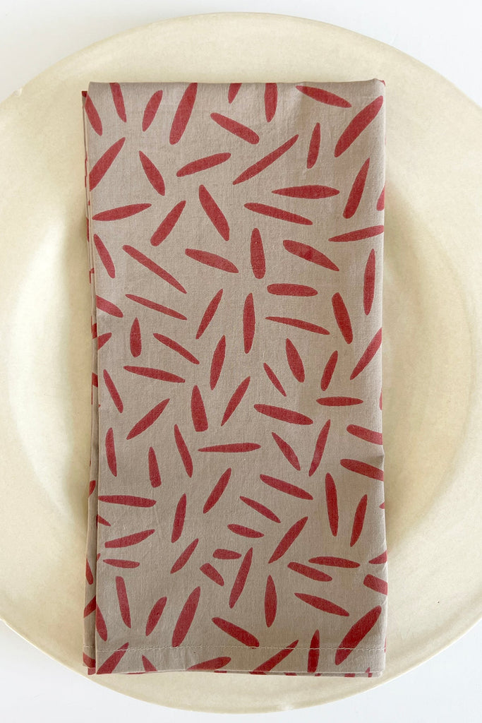 A set of 4 hand painted cotton napkins featuring vibrant red and brown leaf designs from See Design.