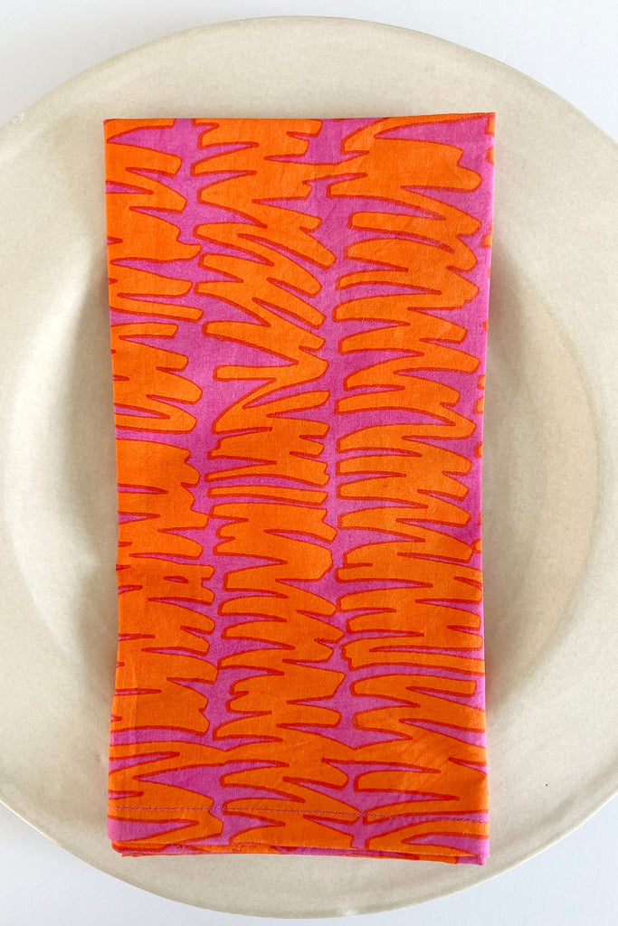 A vibrant See Design cotton napkin (Set of 4) with hand painted designs on a plate.