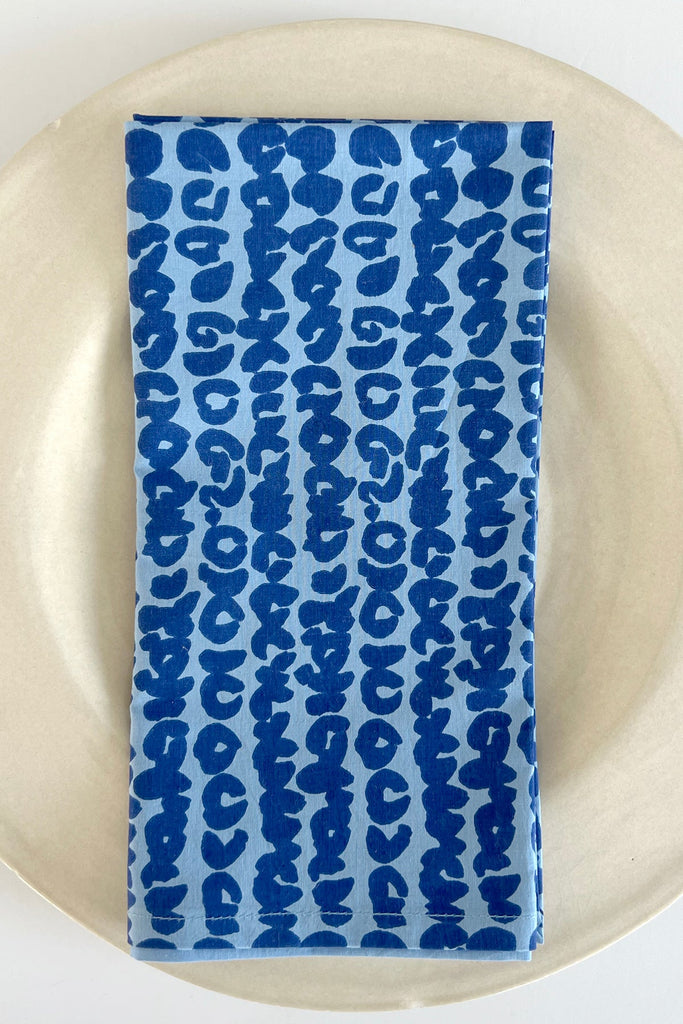 A vibrant plate with a hand painted Blue and White Napkins (Set of 4) by See Design on it.