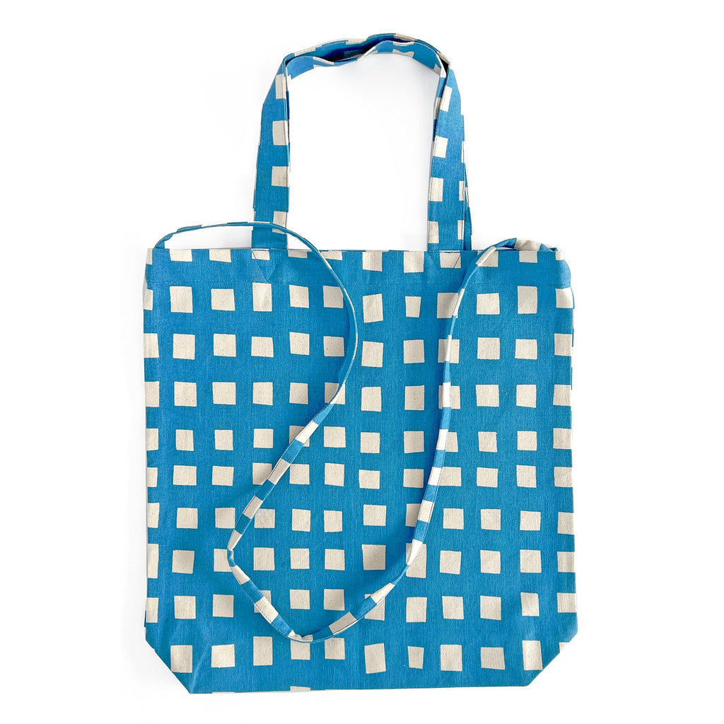 A lightweight Easy Tote Crossbody Bag from See Design, in blue and white checkered canvas, with a crossbody strap.