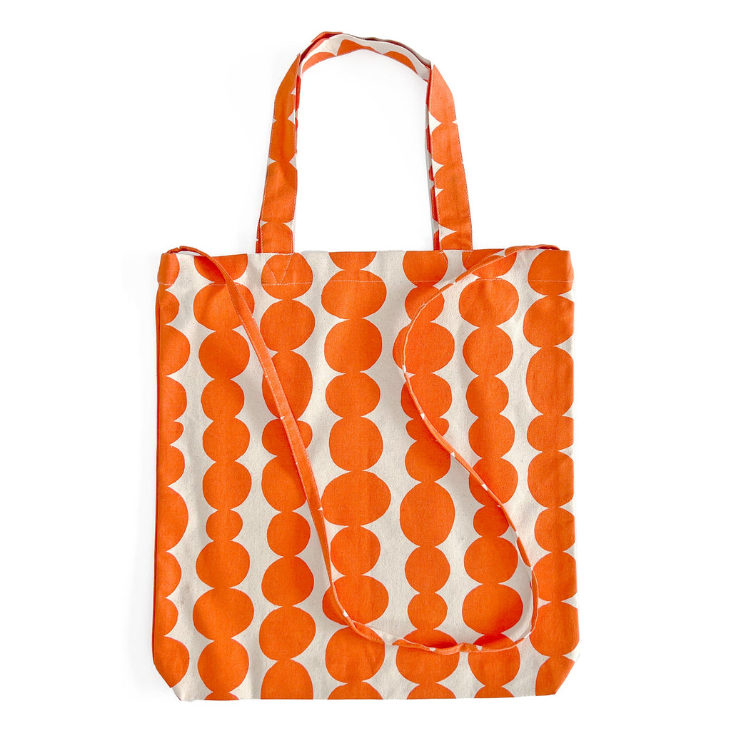 An Easy Tote Crossbody Bag by See Design, in orange and white polka dots on canvas, with a crossbody strap.