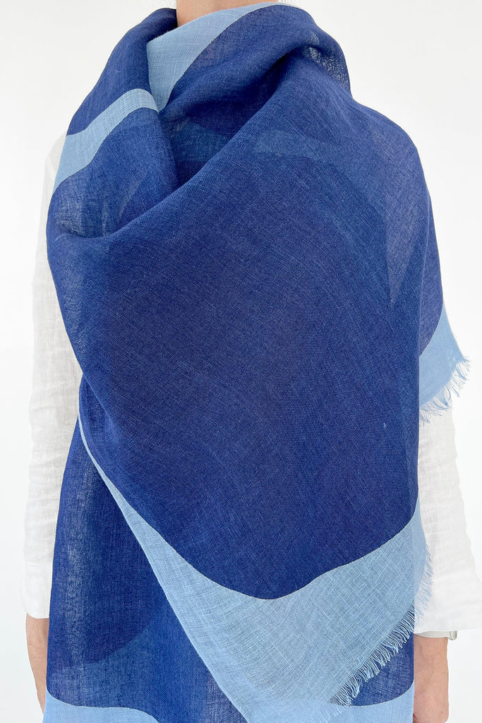 The back view of a woman wearing a colorful See Design linen scarf with a modern design element.