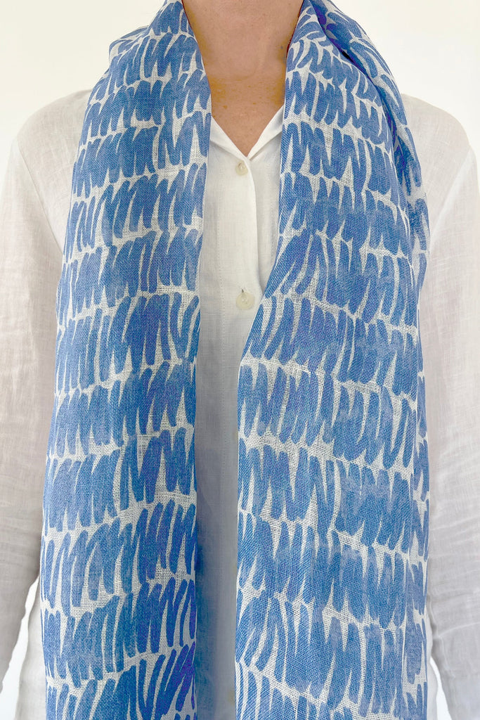 A woman wearing a blue and white See Design linen scarf.