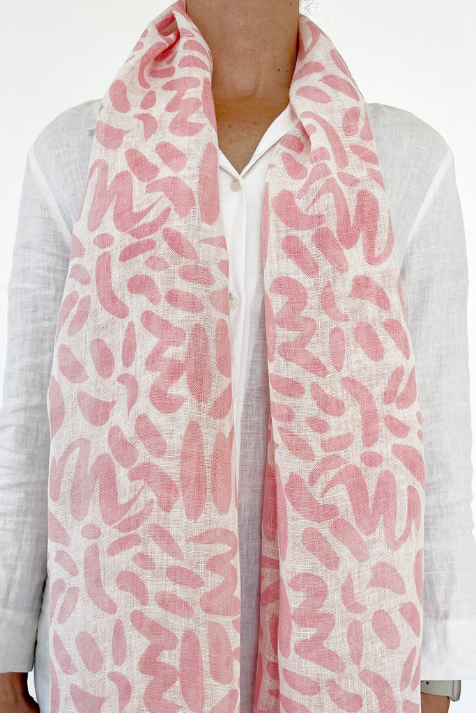 A woman wearing a See Design linen scarf with colorful patterns.