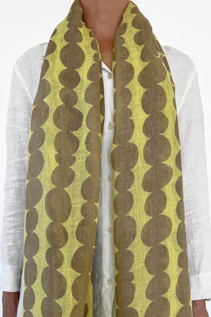 A woman wearing a See Design linen scarf with colorful patterns and a modern design element.