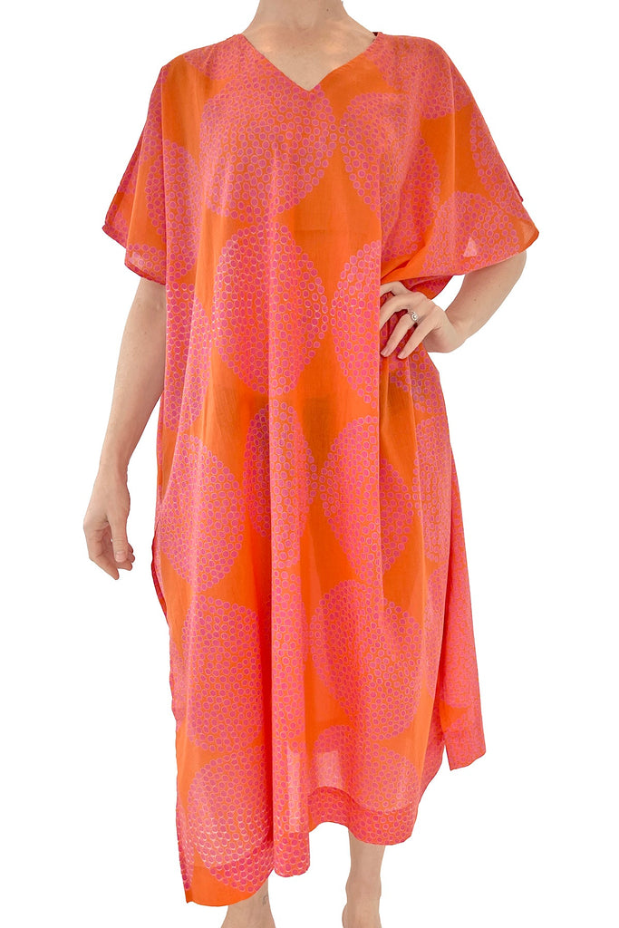 A woman wearing a pink and orange cotton voile Caftan Long dress, perfect as a beach cover up or lounge piece by See Design.