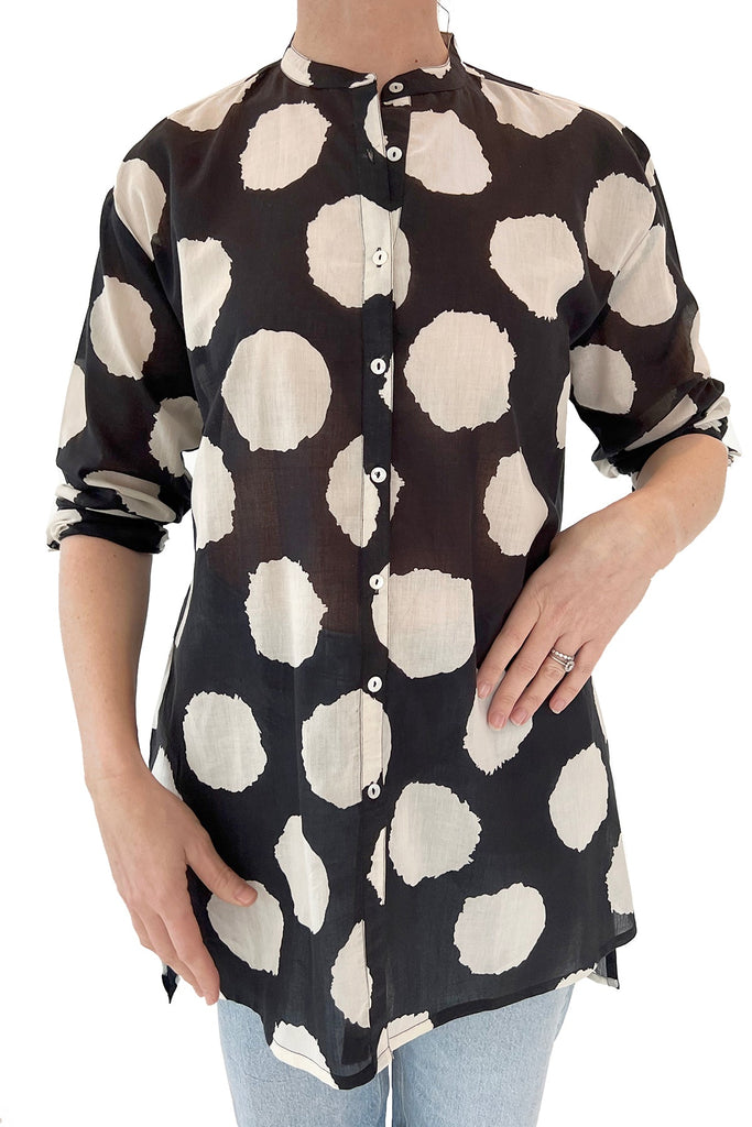 A fashionable woman donning a black and white polka dot long shirt by See Design.