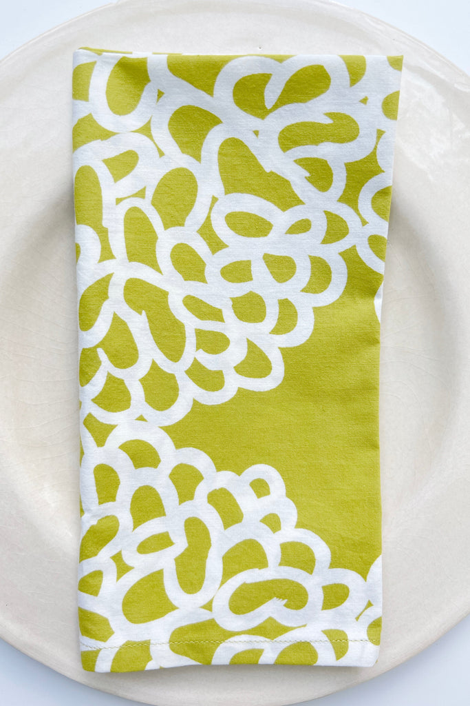 A hand painted See Design green and white Napkins (Set of 4) on a plate.