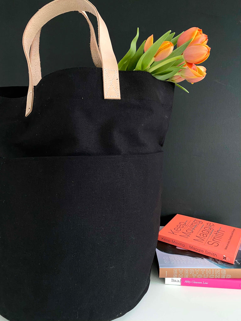 A See Design Tall Circle Tote next to a book and tulips.