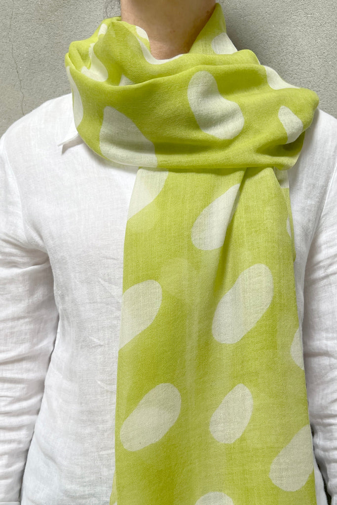 A woman wearing a lime and white See Design wool scarf with beautiful patterns.