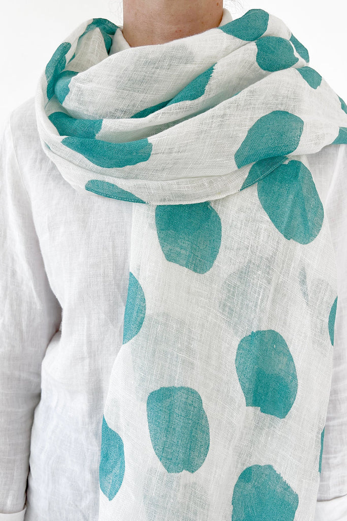 A woman flaunting a Linen Scarf from See Design, with vibrant patterns.