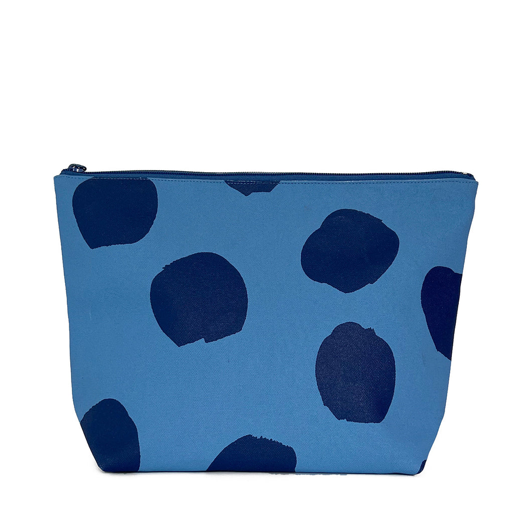 An extra large blue and black polka dot See Design travel pouch for essentials.