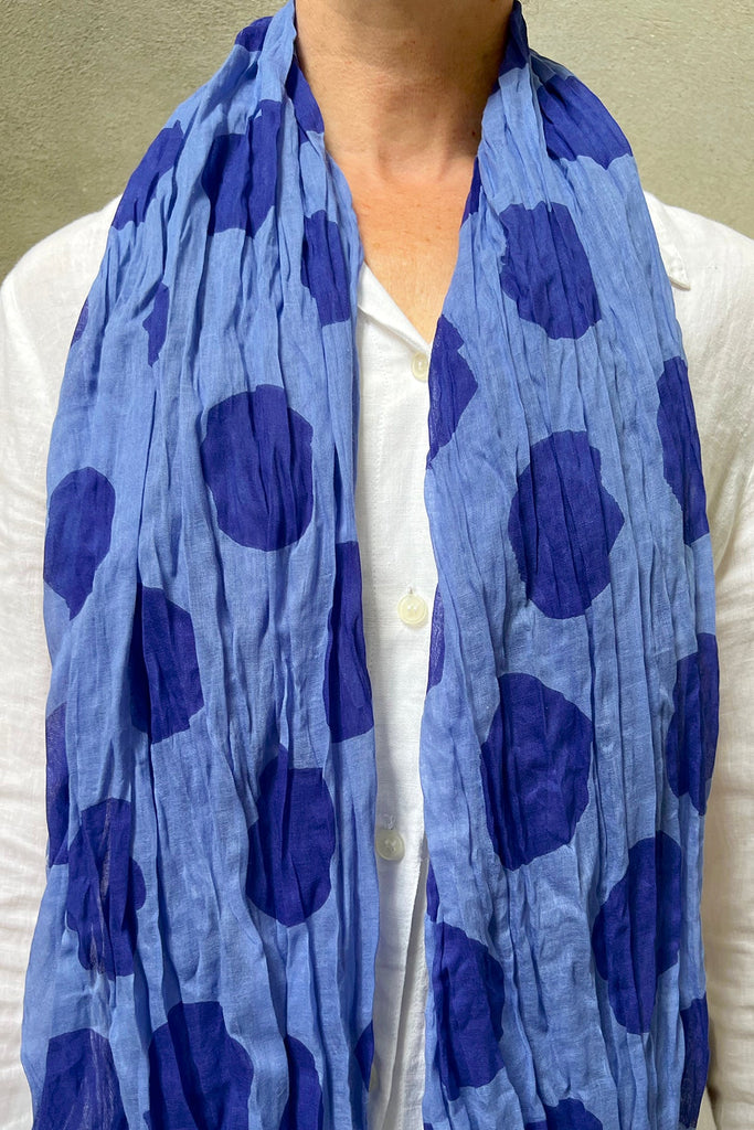 A woman wearing a soft lightweight See Design cotton scarf with bright vibrant shades.