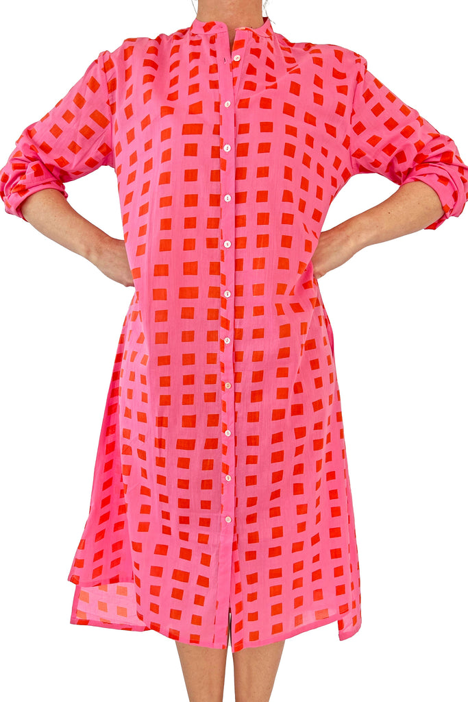 A stylish woman rocking a pink and orange checkered See Design shirt dress.