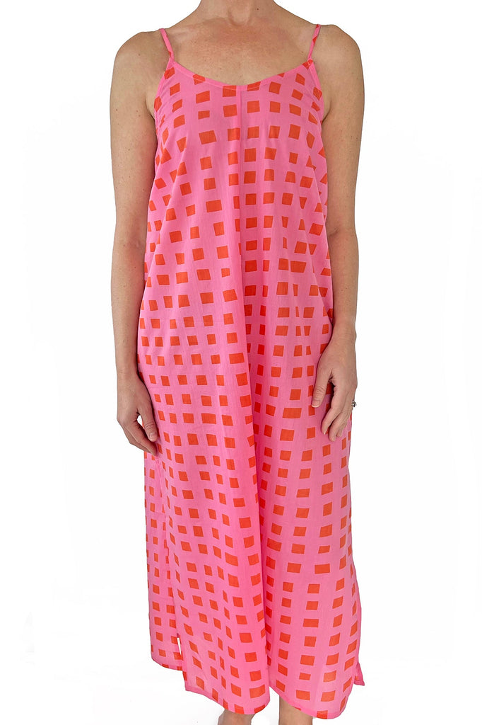 A lightweight slip dress perfect for the beach, worn by a woman in pink and orange checkered print from See Design.