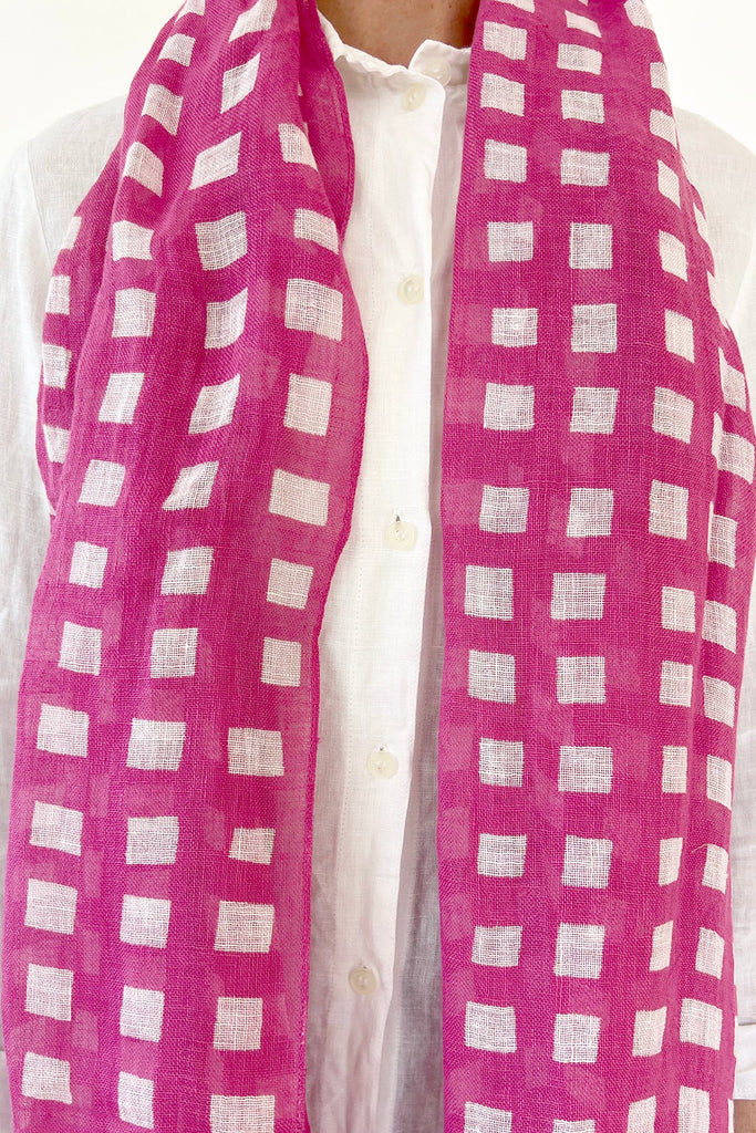A woman wearing a See Design linen scarf with colorful patterns.