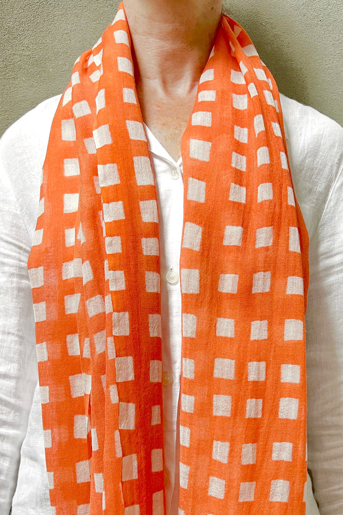 A woman wearing a bright orange See Design wool scarf.