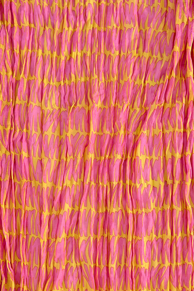 A close up of a crinkled See Design lightweight cotton scarf with delicate shades of pink and yellow.