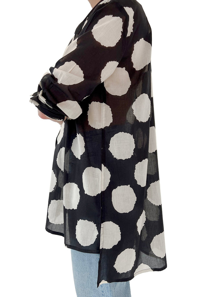 A fashionable woman wearing a black and white polka dot See Design long shirt.