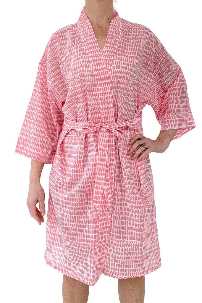 A woman wearing a lightweight pink and white striped See Design kimono robe made of cotton voile.