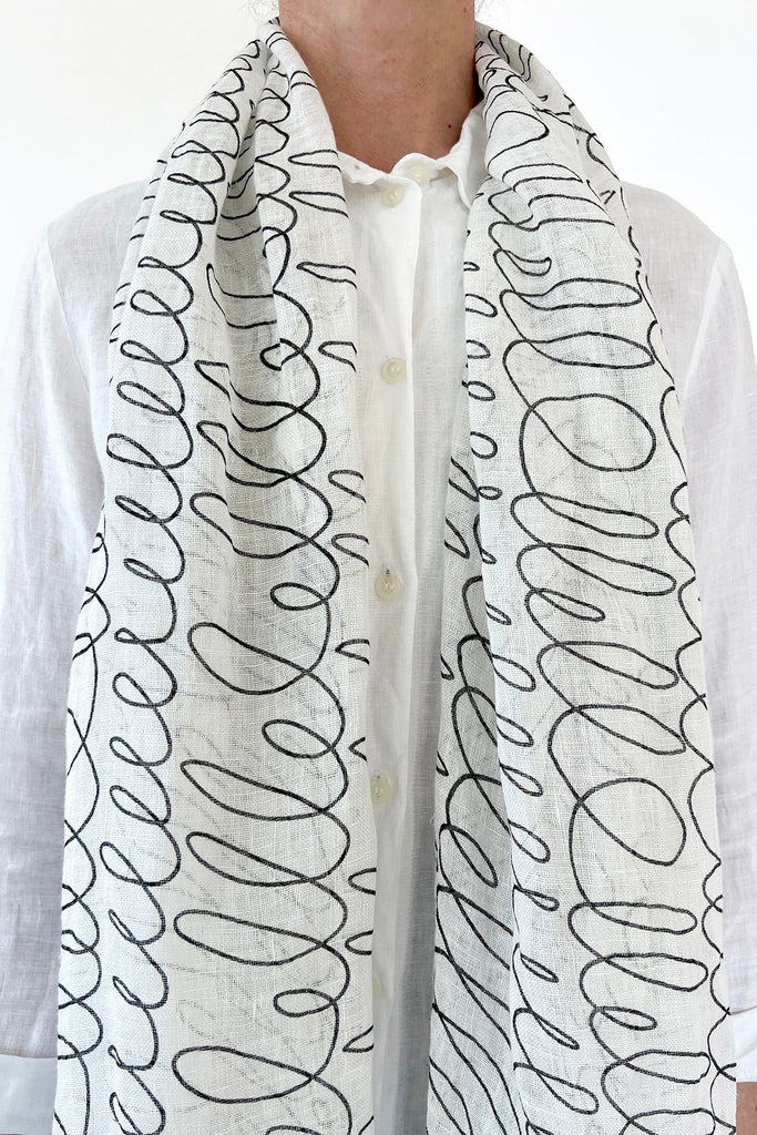 A woman wearing a modern See Design linen scarf with black and white patterns.