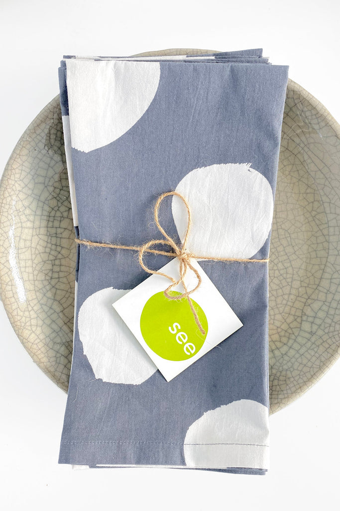 A See Design blue cotton Napkins (Set of 4) on a plate.