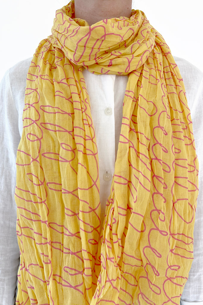 A woman wearing a lightweight See Design cotton scarf with a crinkled texture.