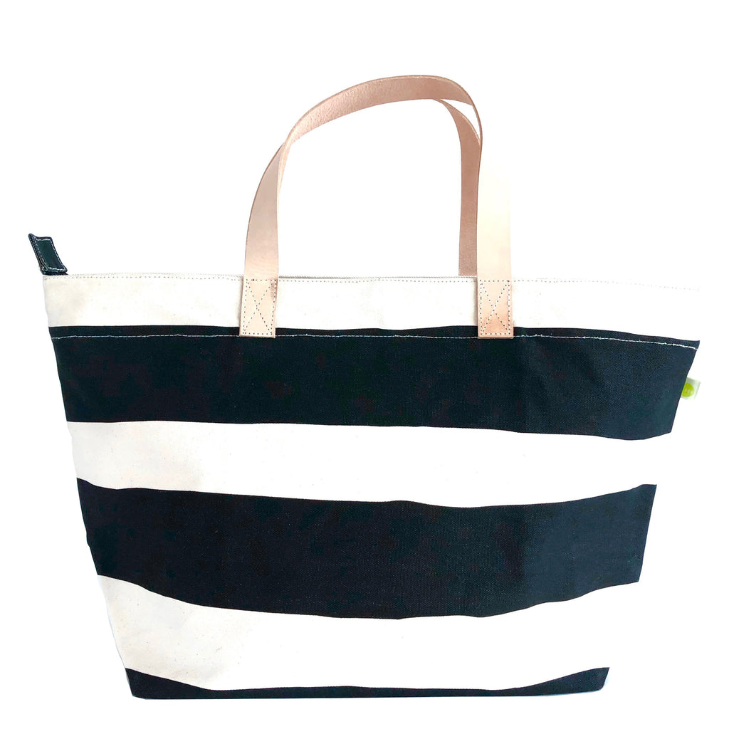 A striped See Design Overnighter tote bag with leather handles, perfect for a weekend away.