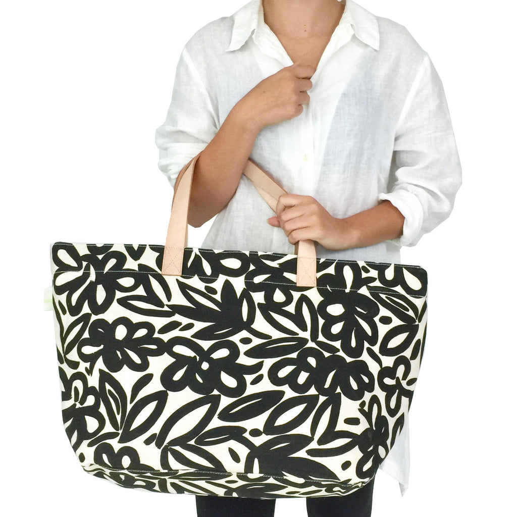 A woman carrying a black and white floral See Design Overnighter on a weekend away.