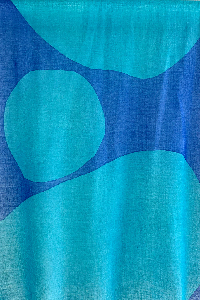 A See Design wool scarf in bright blue hanging on a wall.