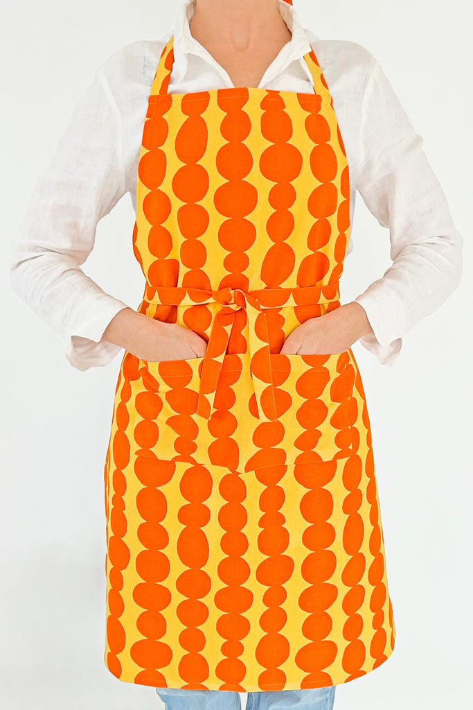 A woman wearing a See Design kitchen apron with hand-painted designs.
