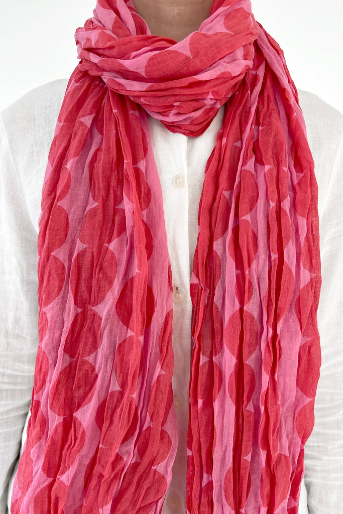 A woman wearing a lightweight pink See Design cotton scarf.