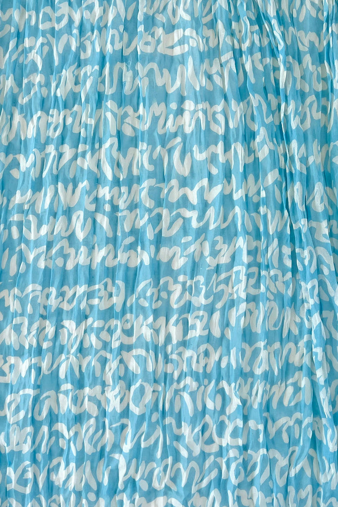 A close up of a See Design lightweight Cotton Scarf with a blue and white print.