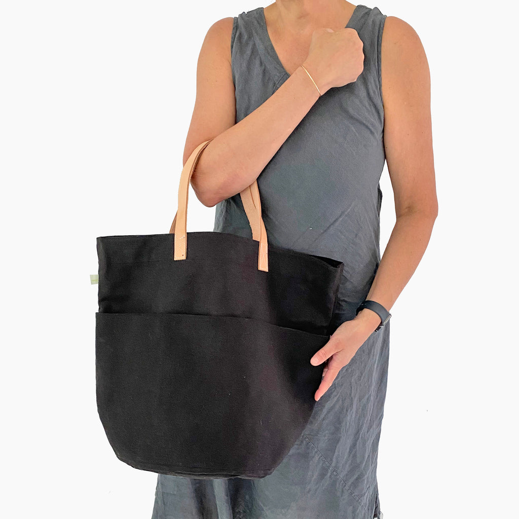 A woman holding a See Design Tall Circle Tote bag.
