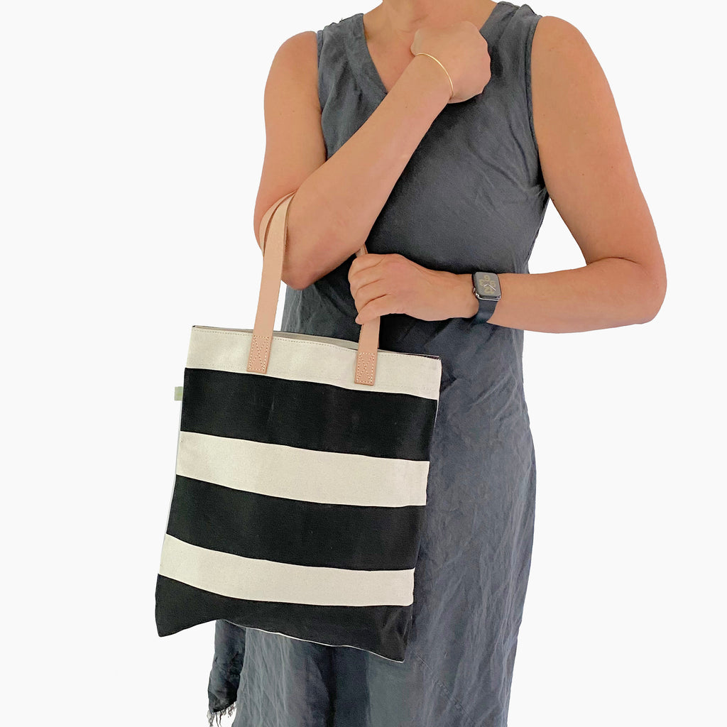 A woman carrying a See Design Tall Tote bag.