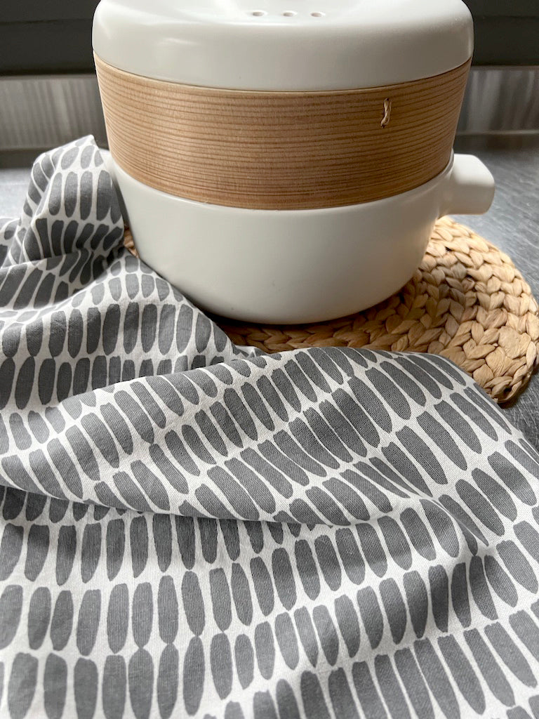 A white bowl sits on top of See Design's Tea Towels (Set of 2).