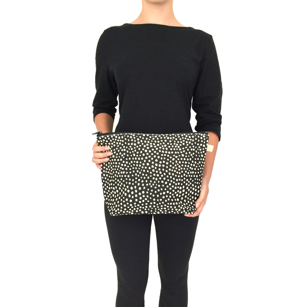 A woman holding a See Design Travel Pouch Extra Large clutch.