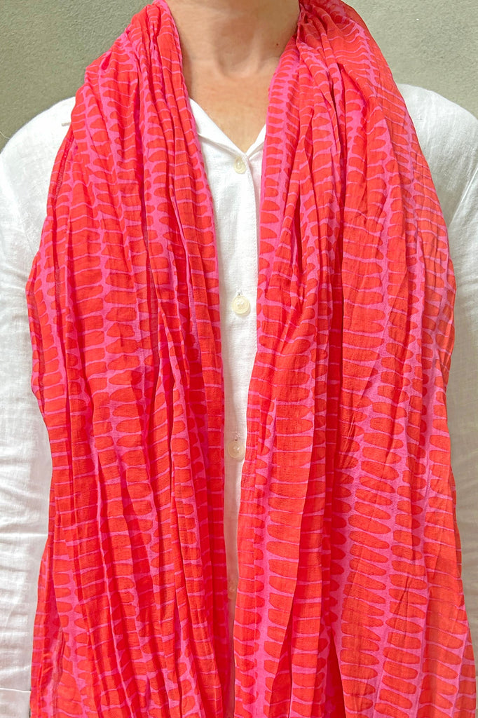 A woman wearing a pink lightweight See Design cotton scarf.